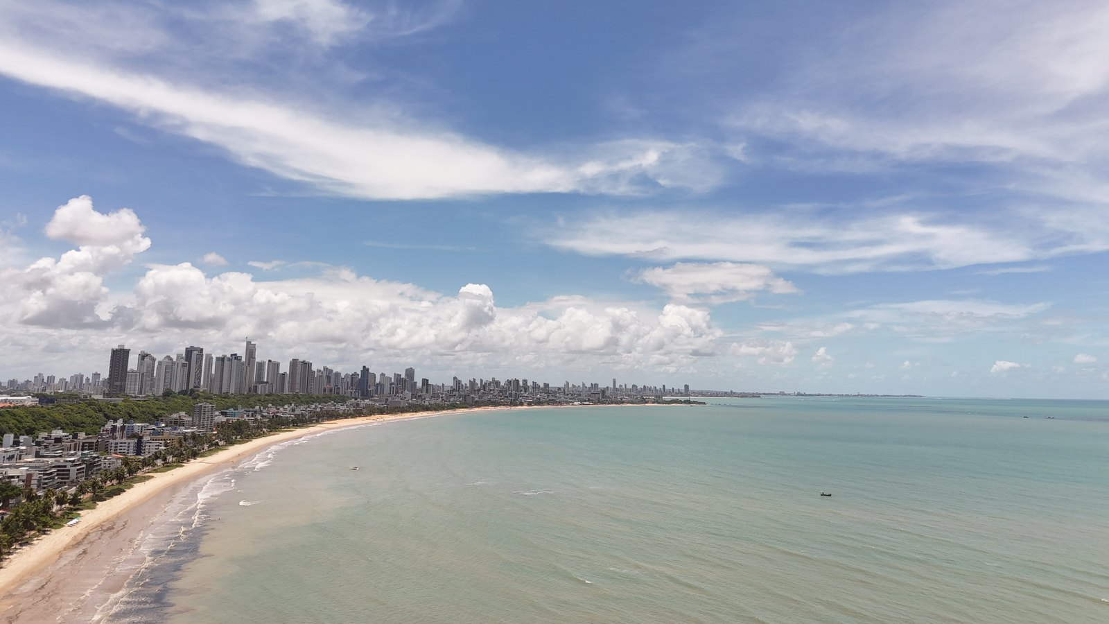 Vista aérea da curva da praia do Cabo Branco com os prédios da orla de João Pessoa ao fundo